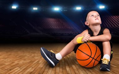 Spor salonu ve büyük zaferler hayalleri katta oturan bir top ile çocuk basketbol oyuncusu.