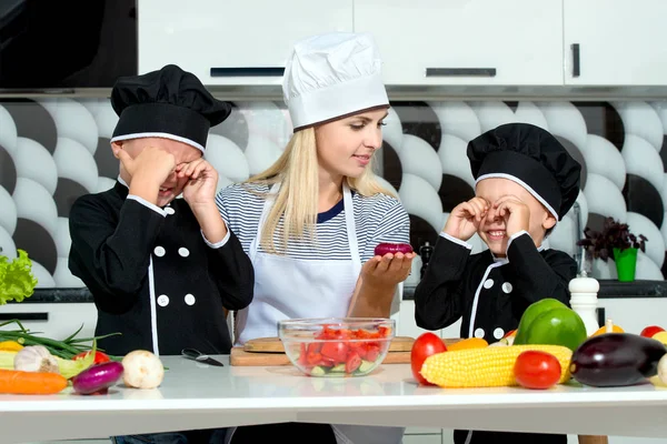 A family of cooks.Healthy eating. Happy family mother and children prepares vegetable salad in kitchen