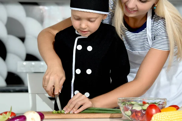 A family of cooks.Healthy eating.Mother and son prepares vegetable salad in kitchen.