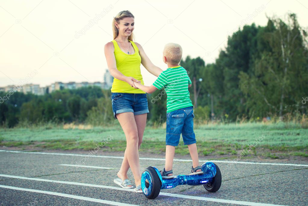 Mother teaches her little son to ride on balance board.