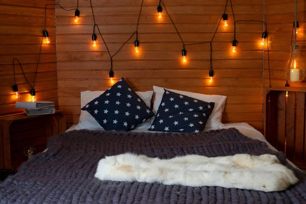 Rustic interior decoration of log cabin bedroom. Cozy warm blanket on bed