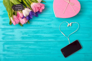 Buket laleler ve bir hediye kutusu ile Sevgililer günü arka plan. Hareket eden telefon ve kulaklık kalp şeklinde. Aşk hakkında romantik müzik.