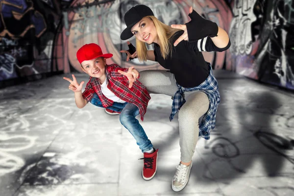 Mother and son dance hip-hop.Urban lifestyle. Hip-hop generation.Graffiti on the walls.