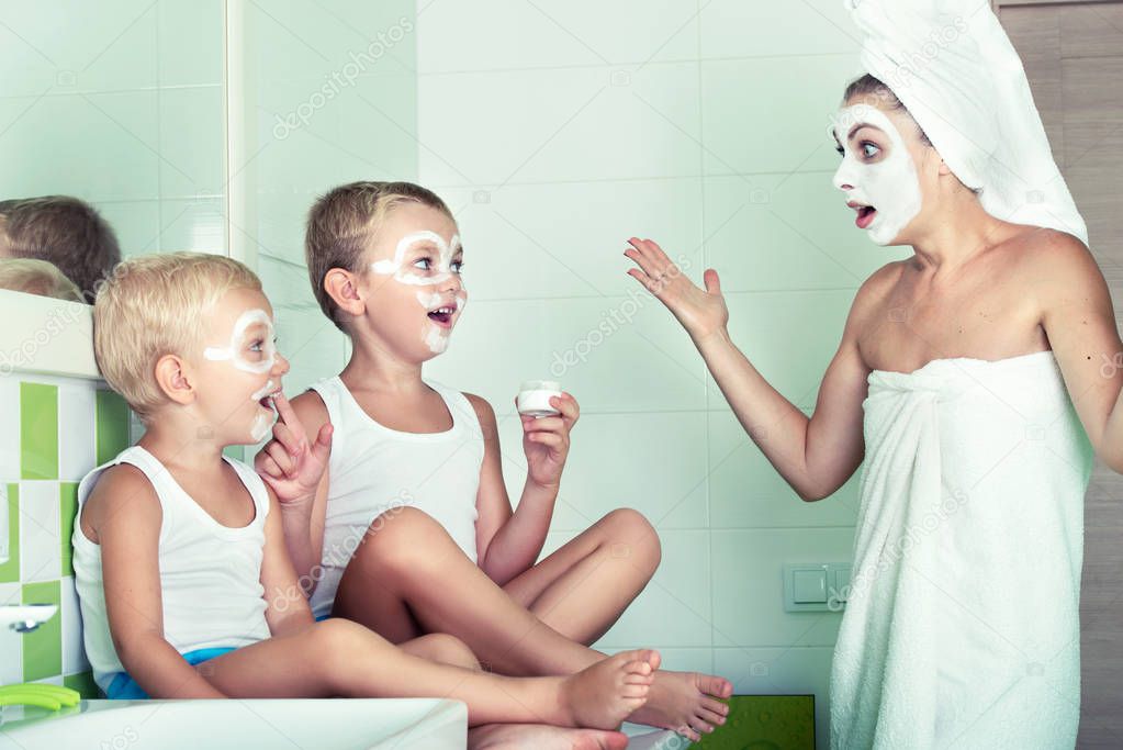 Mother and children make a face mask in the morning.The boys joke with mom. Beauty treatments for the skin