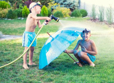 İki kardeş yaz sıcak bir gün bahçede oynamak. Çocuk bir bahçe hortumu ile sıçramasına.