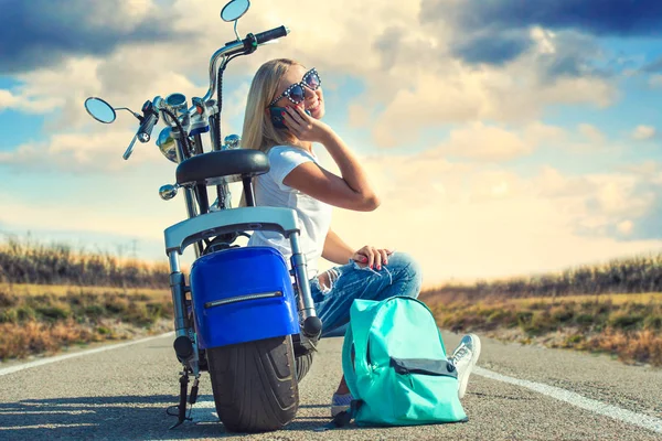 Girl biker sits on a motorcycle. Relax after the trip.