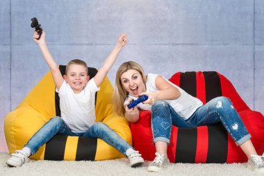 Anne ve oğlu koltuk çantalarına oturur ve video oyunları oynarlar. Duygular..