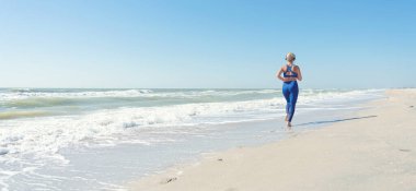 Sahil boyunca sabah koşusu. Sahilde egzersiz yapan kadın, gün doğumuyla tanış. Fitness, spor, yoga ve sağlıklı yaşam tarzı kavramı..