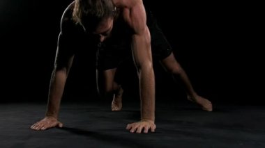 Adam siyah arka plan ile gönderme yapıyor. Yarı çıplak insan, ağır çekim.