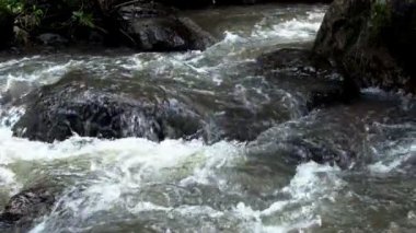 Ağır çekimde kayalar arasında akan temiz dağ nehir azgın. Bulutlu gün açık alınan.