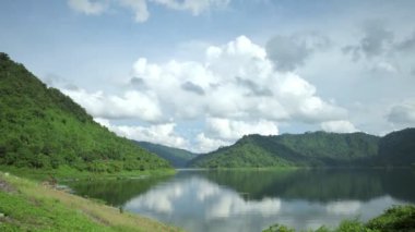 Zaman atlamalı çekim bulutlar ile gölde yansıtan bir baraj çekimde pan. Bulutlu yağmurlu gökyüzü için Clear.