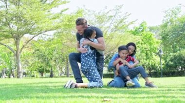 Aile parkta birbirlerini kucaklıyor. Beyaz adam, Çinli kadın ve çocukları ile karışık yarış ailesi. Genç çocuk ve kız birbirlerine sarılmak. Yavaş hareket.