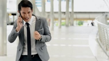 Mobil ofis kavramı. Söz ve sonra istemci başarılı satış pitch cep telefonu üzerinde tezahürat genç Güney Doğu Asya iş adamı. Takım elbise, smokin, doğal ışık açık alınan.