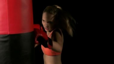 Genç yoğun kadın yumruk atma. Kum delme çanta ve dinlenme. Beyaz genç güzel kadın. Ağır çekimde vurdu. Film bir görünüm filtresi.