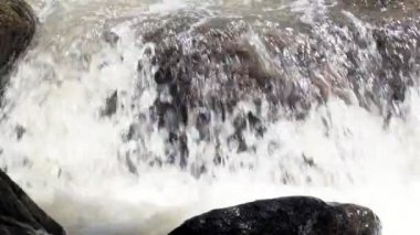 Ağır çekimde kayalar arasında akan temiz dağ nehir azgın. Bulutlu gün açık alınan.