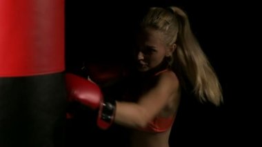 Genç yoğun kadın yumruk atma. Kum delme çanta ve dinlenme. Beyaz genç güzel kadın. Ağır çekimde vurdu. Film bir görünüm filtresi.