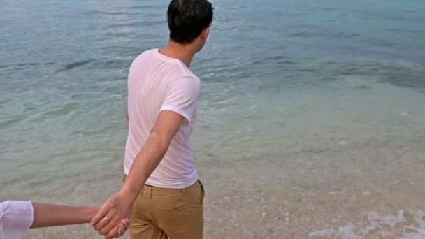 魅力的な若いカップルがビーチで楽しんで ビーチを走る 代前半の白人男性で若い中国の女性 スローモーションで撮影します 映画を見る — ストック動画