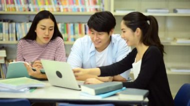 Genç öğrenci Kitaplığı'nda çalışmak. Çalışma yaparken mutlu Asyalı kadın ve erkek üniversite öğrencileri araştırma Danışma, kitapları ile kitaplığındaki defter. Okul eğitim çeşitlilik kavramı için geri. 