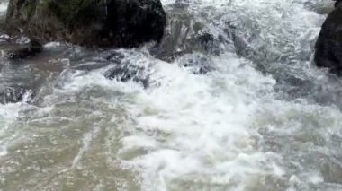 Ağır çekimde kayalar arasında akan temiz dağ nehir azgın. Bulutlu gün açık alınan.