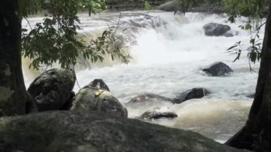 Ağır çekimde kayalar arasında akan temiz dağ nehir azgın. Bulutlu gün açık alınan.