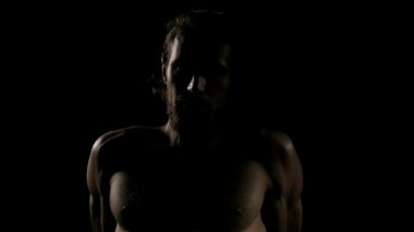 Çok uygun adam siyah arka plan ile egzersiz önce ılık yapıyor. Oturarak ve rahatlatıcı. Ağır çekim.