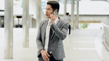 Mobil ofis kavramı. Söz ve sonra istemci başarılı satış pitch cep telefonu üzerinde tezahürat genç Güney Doğu Asya iş adamı. Takım elbise, smokin, doğal ışık açık alınan.