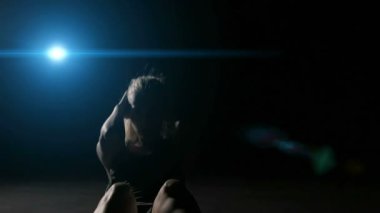 Sportswoman karanlık arka planda sıcak yapıyor