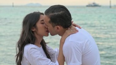 Çekici genç çift romantik sahilde. Tutkulu öpücük güneş sırasında birlikte ayarlayın. Erken 20s beyaz adamla Genç Çinli kadın. Karışık yarış. Ağır çekimde vurdu. Film bak.
