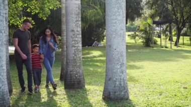 Genç bir aile parkta yürüyor.