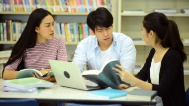 Genç öğrenci Kitaplığı'nda çalışmak. Çalışma yaparken mutlu Asyalı kadın ve erkek üniversite öğrencileri araştırma Danışma, kitapları ile kitaplığındaki defter. Okul eğitim çeşitlilik kavramı için geri. 
