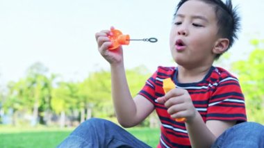 Parkta kabarcık üfleme genç çocuk. Asya çocuk zevk oyun ile onun kabarcık karışım içinde Park.