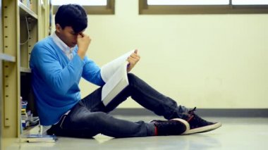 Kütüphane genç öğrenci çalışmada zor. Asyalı erkek üniversite öğrenci zemin ve odaklanarak kitap okuma kitaplığındaki çalışma araştırma yapıyor. Okul eğitim çeşitlilik kavramı için geri.