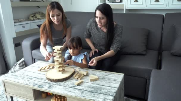小女孩玩游戏与母亲和亚洲保姆在起居室 美丽的白色孩子玩块与她的母亲和漂亮的年轻亚洲保姆在家里下午 — 图库视频影像