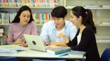 Genç öğrenci Kitaplığı'nda çalışmak. Çalışma yaparken mutlu Asyalı kadın ve erkek üniversite öğrencileri araştırma Danışma, kitapları ile kitaplığındaki defter. Okul eğitim çeşitlilik kavramı için geri. 