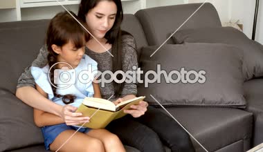 Oturma odasında bir kitap okuma anne kucağına oturan genç kız. Güzel beyaz çocuk öğleden sonra evde annesi ile çalışma.