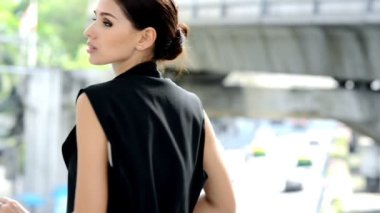 İş bölgesinde bir yürüyüş şekilde duran bir çekici ve kendine güvenen genç beyaz iş kadın portresi. Ona dokunmak yüz ve arka planda trafik ile gülümse.