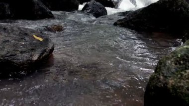 Ağır çekimde kayalar arasında akan temiz dağ nehir azgın. Bulutlu gün açık alınan.