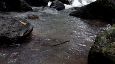 Ağır çekimde kayalar arasında akan temiz dağ nehir azgın. Bulutlu gün açık alınan.