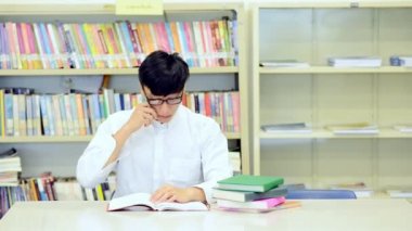 Kütüphane genç öğrenci çalışmada zor. Asyalı erkek üniversite öğrenci Danışma ve gülümseyen kitapları ile kitaplığındaki çalışma araştırma yapıyor. Okul eğitim çeşitlilik kavramı için geri. 