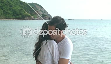 Çekici genç çift romantik sahilde. Tutkulu öpücük güneş sırasında birlikte ayarlayın. Erken 20s beyaz adamla Genç Çinli kadın. Karışık yarış. Ağır çekimde vurdu. Film bak.
