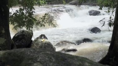 Ağır çekimde kayalar arasında akan temiz dağ nehir azgın. Bulutlu gün açık alınan.