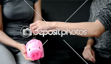 Aile kavramları kaydetme. İki güzel kız kanepe ve piggy banka koyarak sikke para dinlenin.