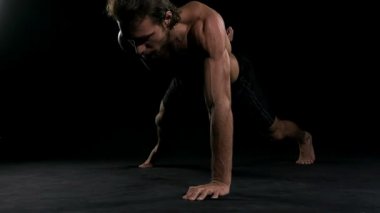 Adam siyah arka plan ile gönderme yapıyor. Yarı çıplak insan, ağır çekim.