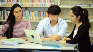 Genç öğrenci Kitaplığı'nda çalışmak. Çalışma yaparken mutlu Asyalı kadın ve erkek üniversite öğrencileri araştırma Danışma, kitapları ile kitaplığındaki defter. Okul eğitim çeşitlilik kavramı için geri. 