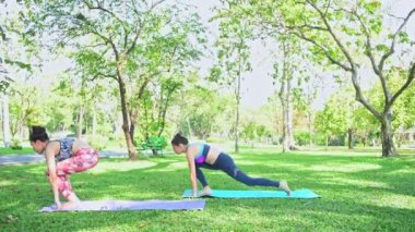 Kadın parkta Yoga öğretir. Yoga yapmak ve halka açık parkta dinlenmek.