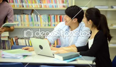 Genç öğrenci Kitaplığı'nda çalışmak. Çalışma yaparken mutlu Asyalı kadın ve erkek üniversite öğrencileri araştırma Danışma, kitapları ile kitaplığındaki defter. Okul eğitim çeşitlilik kavramı için geri. 