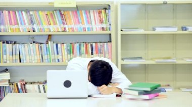 Kütüphane genç öğrenci çalışmada zor. Yorgun Asya erkek üniversite öğrenci Danışma ve yorgun hissediyorum kitap kitaplıkla çalışma araştırma yapıyor. Okul eğitim çeşitlilik kavramı için geri.