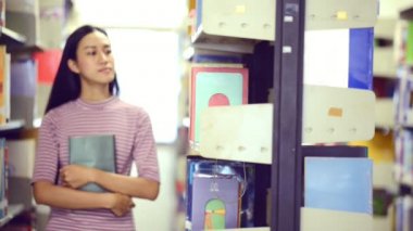 Asya Üniversitesi yaşam kavramı. Üniversite Kütüphanesi kitaplar her çalışmada için arayan yürüyüş genç Genç kız öğrenci. Asyalı kız elbise kırmızı tshirt ve kot pantolon.