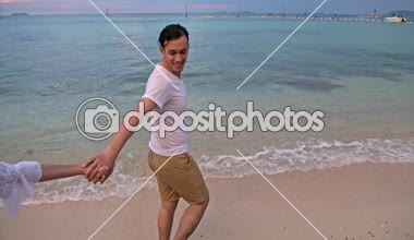 Çekici genç çift sahilde eğleniyor. Kumsalda çalıştırıyor. Erken 20s beyaz adamla Genç Çinli kadın. Karışık yarış. Ağır çekimde vurdu. Film bak.