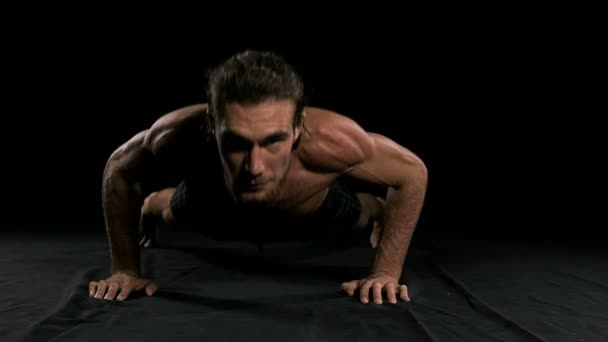 黒の背景でプッシュをやっている男 半分裸の男 スローモーション — ストック動画